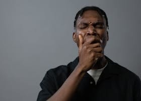 Portrait of a tired man yawning with hand on mouth, showing fatigue and exhaustion.