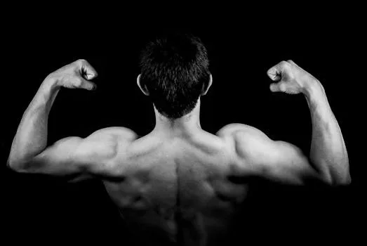 man-male-boy-a-person-50597-50597-1 Black and white photo of a muscular man flexing arms against a dark background.